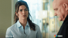 a woman in a blue shirt is talking to a bald man in a nbc advertisement