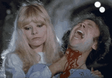a woman is holding a bloody man in her arms .