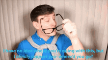 a man in a blue shirt is holding a pair of glasses in front of his face
