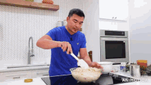 a man in a blue shirt is stirring something in a bowl with a spatula
