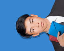 a young man in a suit and tie is holding a blue book