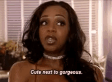 a woman wearing a choker is talking about being cute next to gorgeous .