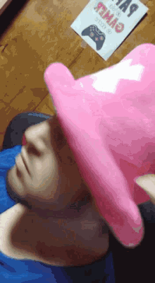 a person wearing a pink hat laying on a wooden table