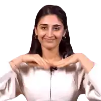 a woman making a heart shape with her hands while wearing a white jacket