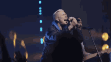 a man playing drums in front of a microphone with a blue background