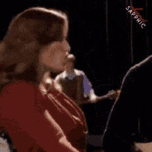 a woman in a red shirt is talking to another woman