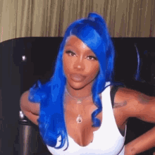 a woman with blue hair is wearing a white tank top and necklace .