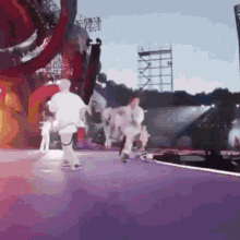 a group of people are running on a stage with a purple background .
