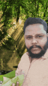 a man with a beard is standing in front of a green forest