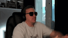 a man wearing headphones and sunglasses is sitting in front of a window .