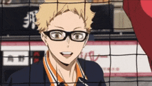 a volleyball player wearing glasses is smiling behind a volleyball net .