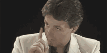 a man in a white suit is pointing at the camera with the words `` you got this '' written in yellow .