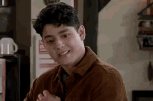 a young man with curly hair is smiling and looking at the camera .