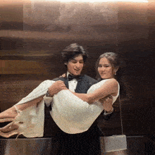 a man is carrying a woman in a white dress