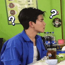 a man in a blue shirt is sitting at a table with pepsi bottles in front of him