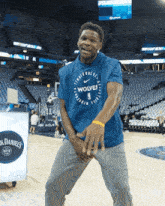 a man wearing a blue shirt that says wolves stands on a basketball court