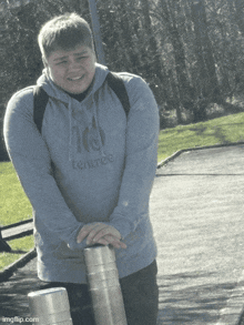 a young man wearing a tentree hoodie holds a metal pole
