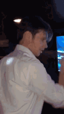 a man in a white shirt is dancing in front of a television