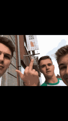 three young men pose for a picture in front of a sign that says brewery