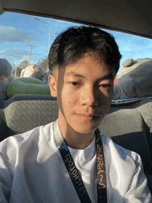 a young man in a car with a lanyard around his neck that says ' poloh12 ' on it