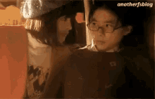 a girl and a boy are sitting next to each other and the girl is wearing glasses