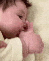 a baby is biting its hand while laying down