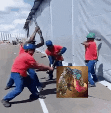 a group of men in red shirts and blue pants are working on a wall