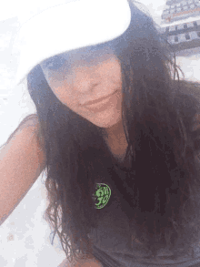 a woman wearing a white hat and a gray shirt with a green sticker that says 50 on it