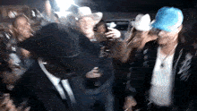 a man in a cowboy hat is dancing in a crowd of people