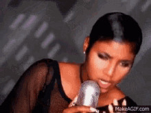 a woman is singing into a microphone while wearing a black shirt .