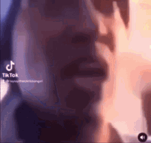 a close up of a person 's face with a blurred background and a tiktok logo .