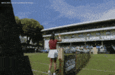 a woman stands on a tennis court in front of a sign that says " international lawn tennis "