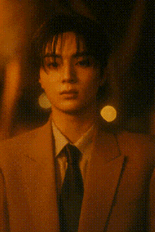 a young man wearing a suit and tie is standing in front of a yellow wall
