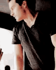 a man wearing a black and white striped shirt is standing in a room .
