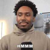 a man wearing a hoodie with the word hmm on the front