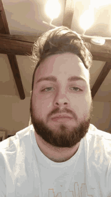 a man with a beard is wearing a white t-shirt with a cityscape on it