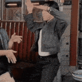 a woman in a denim jacket is dancing in a diner with her hands in the air