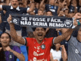 a man in a red shirt holds up a scarf that says se fosse facil