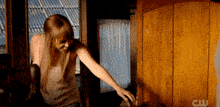 a woman is standing in front of a wooden door with the letters cw on it