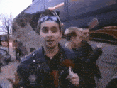 a man wearing sunglasses and a headband stands in front of a van that says ' a & a ' on it