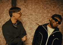 two men are standing next to each other in front of a wall full of money .
