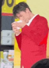a man in a red suit is holding a cup of coffee in his hand .