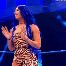 a woman with blue hair is wearing a zebra print dress .