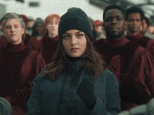 a woman in a beanie stands in front of a group of people