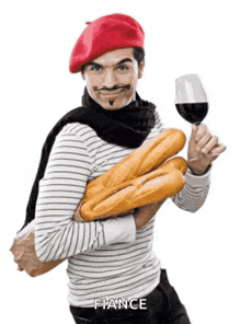 a man wearing a red beret is holding a glass of wine and bread