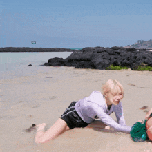 a woman is crawling on a beach with a sign in the background that says t.