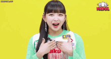the girl is wearing a green shirt and earrings and has the word sayang on her chest .