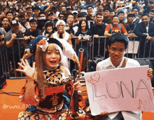a girl with a violin holds a sign that says luna