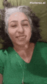 a woman in a green shirt is smiling and wearing headphones .