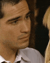 a man in a white shirt and tie looks at a woman
